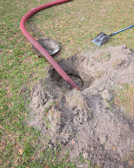 Vacuum hose run into an opened septic tank lid during a pump-out